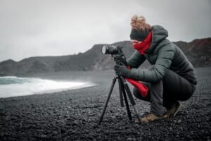 Female photographer using a tripod on a rocky coast